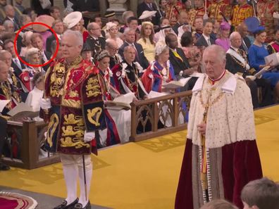 King Charles stands in Westminster Abbey during his coronation. Prince Harry can be seen in the background.