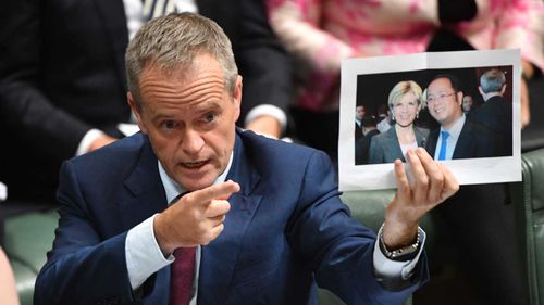 Bill Shorten holds a photograph of Julie Bishop and Chinese businessman Huang Xiangmo.