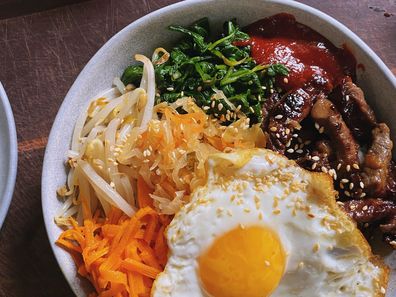 A bowl of beef bibimbap, with veggies and an egg