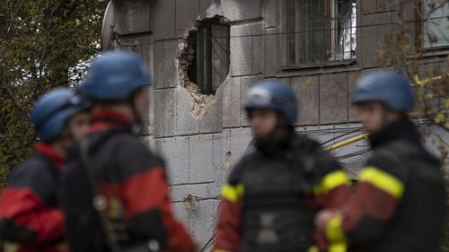 Пожарные стоят рядом со зданием, пострадавшим в результате российской атаки в Запорожье, Украина, в пятницу, 21 октября 2022 года. (AP Photo/Leo Correa)