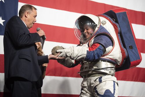 Kristine Dans hands a rock to NASA administrator Jim Bridenstine during a demonstration of the Exploration Extravehicular Mobility Unit (xEMU), one of two NASA spacesuit prototypes for lunar exploration on Tuesday, Oct. 15, 2019, at NASA Headquarters in Washington. 