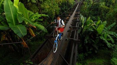 A 100-foot bridge barely wider than a bike tyre spanning a bridge in Java may very well be the world's most dangerous school run. (All images Getty)