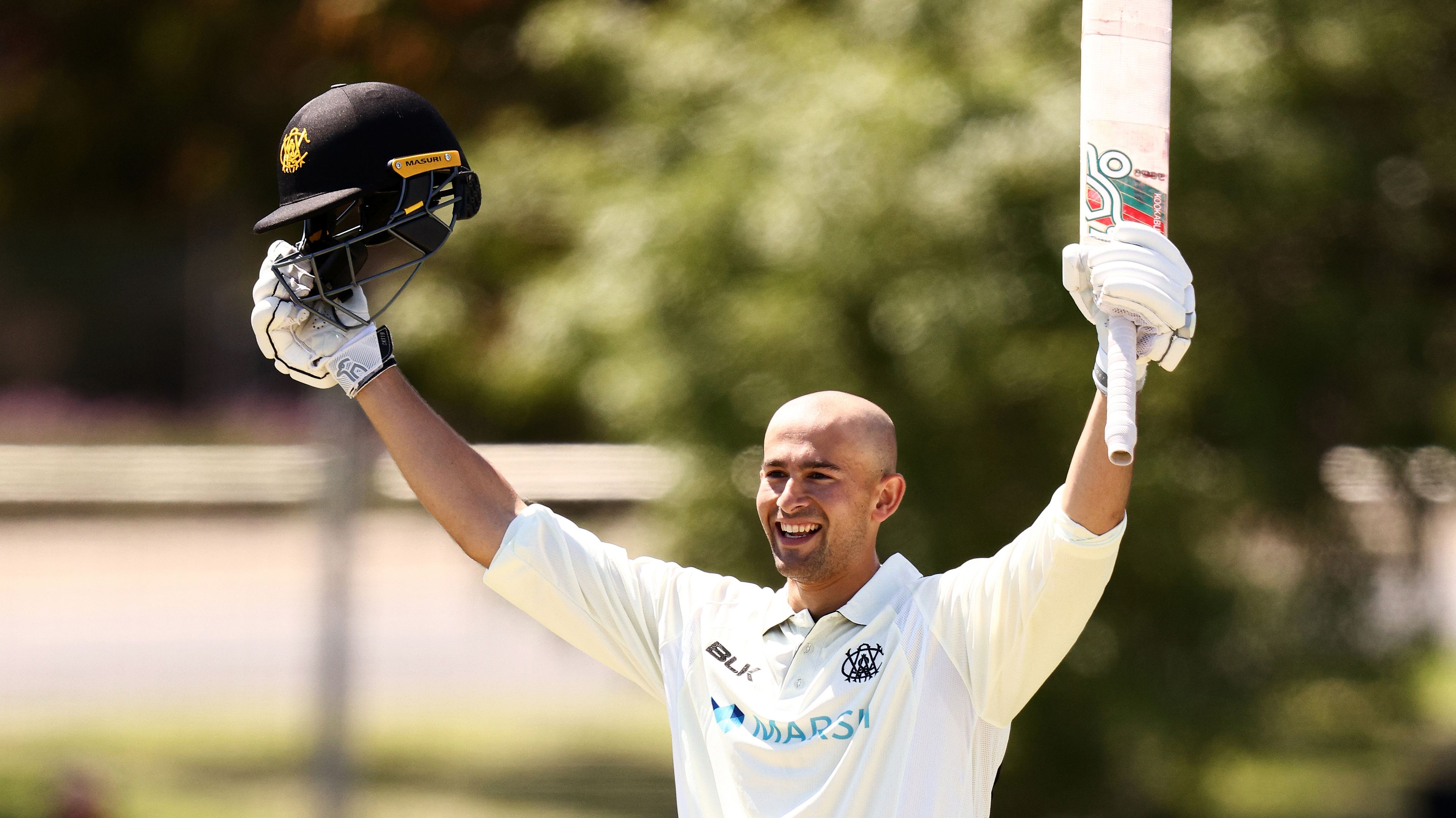 Ashton Agar raises his bat triumphantly as he celebrates a century.