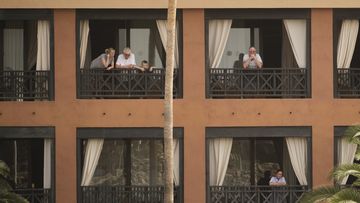 People stand on their balconies of the H10 Costa Adeje Palace after the hotel went into lockdown following two guests testing positive for coronavirus.
