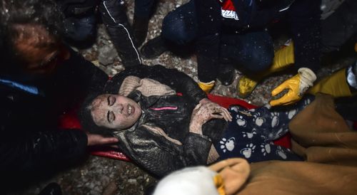 Rescue workers and medics carry a woman out of the debris of a collapsed building in Elbistan, Kahramanmaras, in southern Turkey.