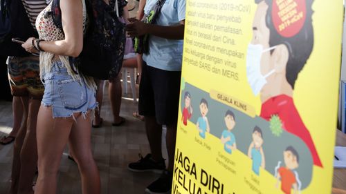 Foreign tourists stand near an information banner on the new coronavirus