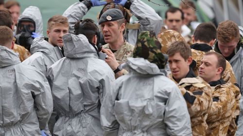 Soldiers in protective gear investigate