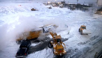 Front loaders dump snow into a melter while clearing the apron around Gates C and D at Terminal B at LaGuardia Airport, Thursday, Jan. 4, 2018, in New York. All flights have been suspended temporarily at JFK and LaGuardia airports due to wind and whiteout conditions. (AP Photo/Julie Jacobson)
