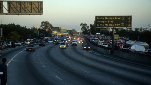 Police cars pursue the Ford Bronco driven by Al Cowlings, carrying then fugitive murder suspect O.J. Simpson, on a slow-speed car chase June 17, 1994 on the 405 freeway in Los Angeles, California. Simpson's friend Cowlings eventually drove Simpson home, with Simpson ducked under the back passenger seat, to Brentwood where he surrendered after a stand-off with police.