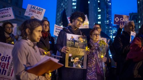 Bahij Chancey, 26, center, holds a photo of his friend and, one of the victims Nicholas Cleves, during an interfaith vigil for peace at Foley Square. (AAP)