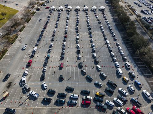 Cars line up in a parking lot at NRG Park as people wait to receive a COVID-19 vaccine at a federally supported supersite at the Harris County facility, Wednesday, Feb. 24, 2021, in Houston