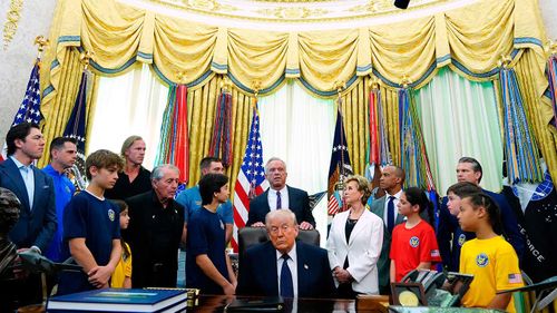 Donald Trump circondato da membri del gabinetto e bambini.