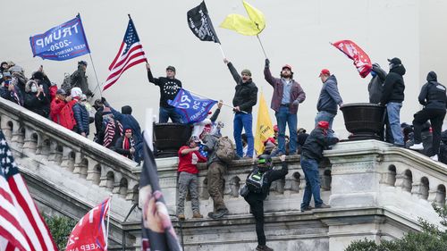 ARQUIVO - Manifestantes agitam bandeiras na frente oeste do Capitólio dos EUA em Washington em 6 de janeiro de 2021. (AP Photo/José Luis Magaña, Arquivo)