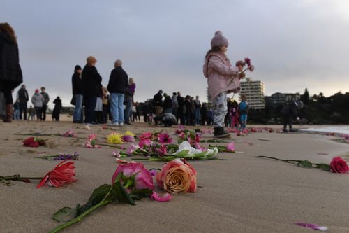 Friends and family held a vigil for Justine in Freshwater, Sydney, throwing pink flowers into the sea. Picture: AAP