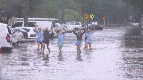 Schoolkids walking through floodwaters in Manly Vale.