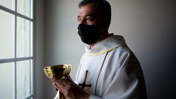 Father Andres Arango distributes Holy Communion while wearing a mask amid the COVID-19 pandemic at Gordon Hall at St. Gregory&#x27;s Catholic Church in Phoenix on May 10, 2020. St. Gregory&#x27;s Catholic Church Communion COVID-19