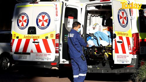 A NSW ambulance paramedic helps a patient into a Sydney hospital.