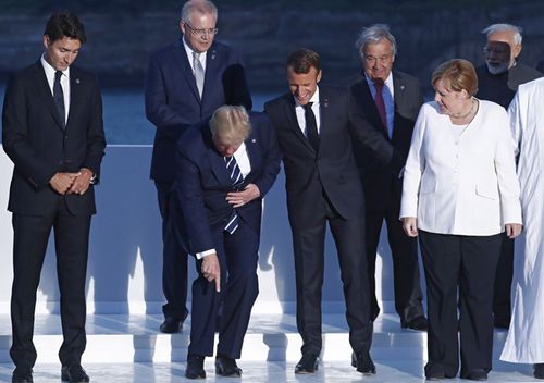 US President Donald Trump makes a joke during the 'family photo' at the G7 summit. Standing around Mr Trump are Canadian Prime Minister Justin Trudeau, French President Emmanuel Macron, German Chancellor Angela Merkel, Australian Prime Minister Scott Morrison, UN Secretary General Antonio Guterres and Indian Prime Minister Narendra Modi