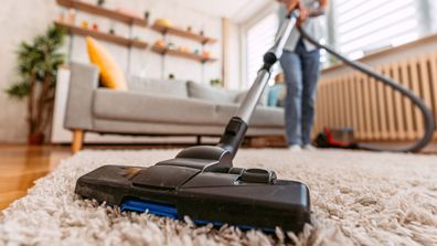 Woman vacuuming the carpet in her apartment.