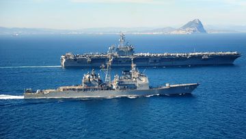 The Ticonderoga-class guided missile cruiser USS Vicksburg  escorts the Nimitz-class aircraft carrier USS Theodore Roosevelt by the Rock of Gibraltar in March, 2015.  The USS Theodore Roosevelt is now sailing in the South China Sea.