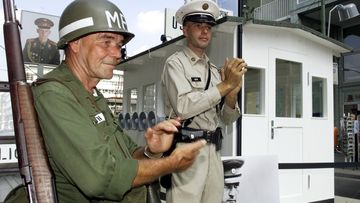 Two unidentified Germans dressed like US-Military Police pose during the openig ceremony in front of an original copy of the first border control house at the Checkpoint Charlie in Berlin Sunday, August 13, 2000.