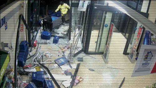 The men eventually drag the cash machine through the shattered doors.  