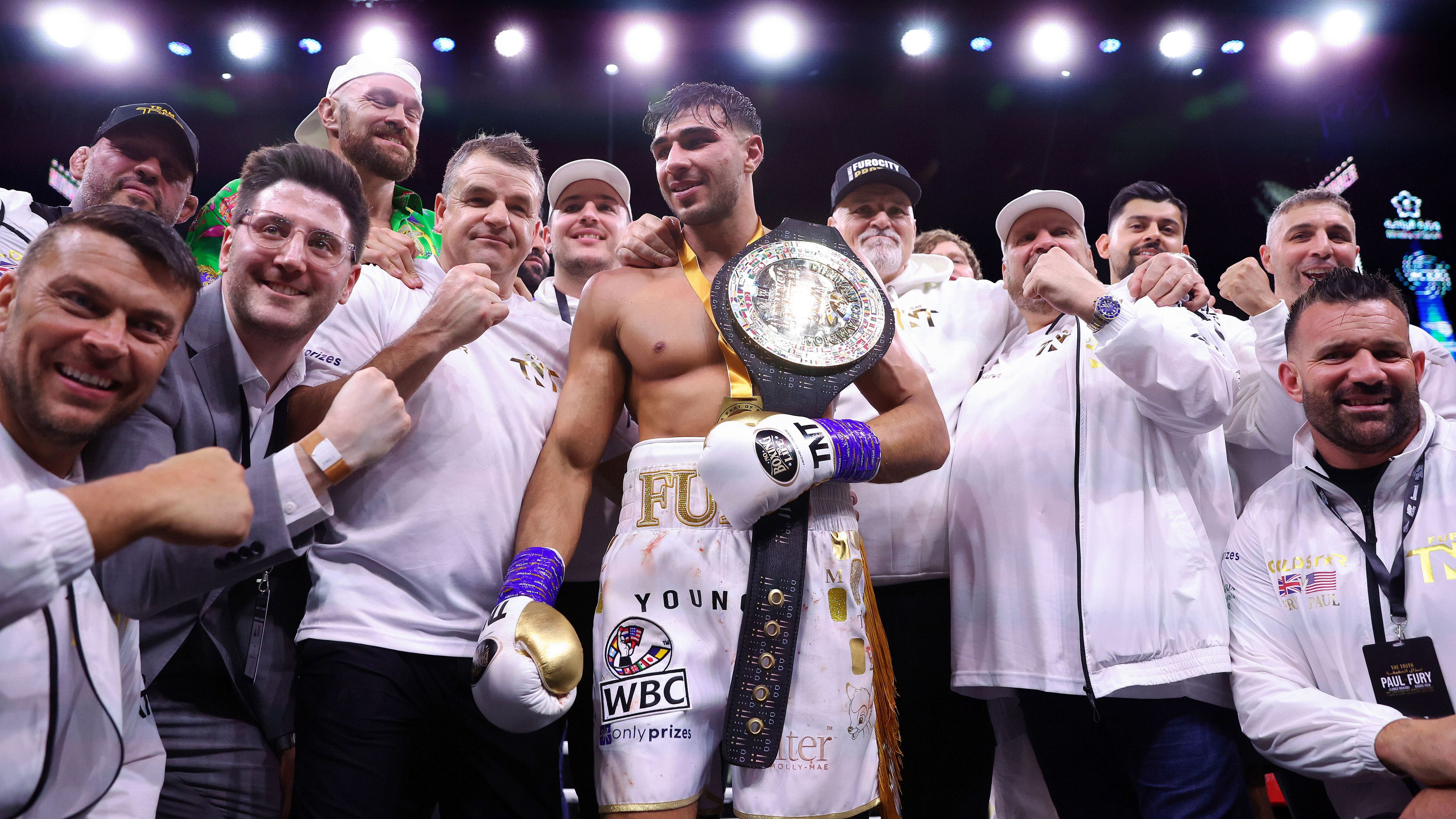 Tommy Fury celebrates with his team as they pose for a photo with their title belt after he defeated Jake Paul.