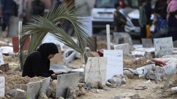 Palestinians visit the graves of people killed in the Israeli bombardment of the Gaza Strip and buried inside the Shifa Hospital grounds in Gaza City