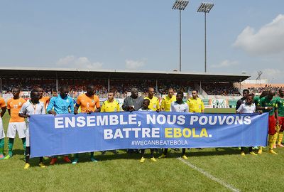 The teams lined up alongside a banner saying 'Together we can defeat Ebola'.