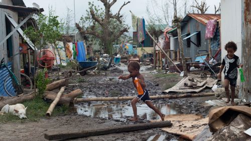 Children play amidst rubble in a street after Cyclone Pam hit Vanuatu island, South Pacific region. (AAP)