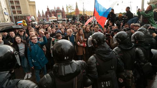 Riot police officers block protesters with Russian flags during a rally in Moscow on Vladimir Putin's birthday. (AP)