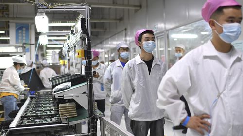 Workers line up to get tested for COVID-19 at the Foxconn factory in Wuhan in central China's Hubei province in August 2021.