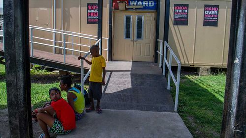 Children sit outside a ward of Port Moresby General Hospital.