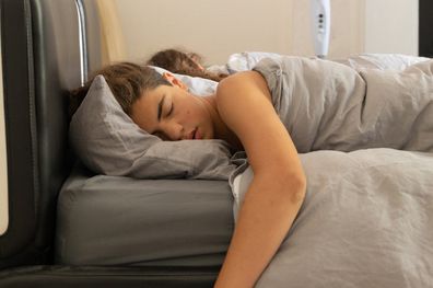 A boy and a girl sleep refreshed by a fan on black leather bed. Copy space