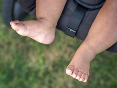 Baby feet dangling off a stroller.