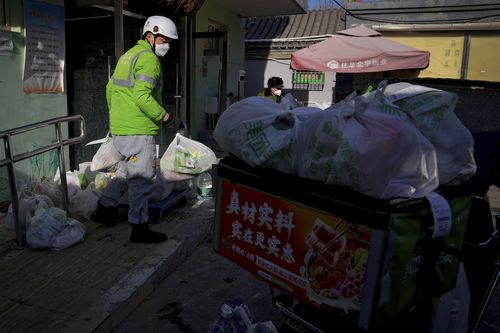 Un fattorino raccoglie sacchi di ordini di generi alimentari online mentre un'ondata di casi di COVID-19 causa una carenza di addetti alle consegne a Pechino, domenica 18 dicembre 2022 (AP Photo/Andy Wong)