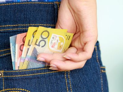 Woman placing Australian money in her back pocket.