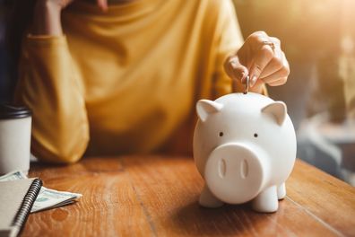 woman hand putting money coin in piggy bank for saving money and financial concept.