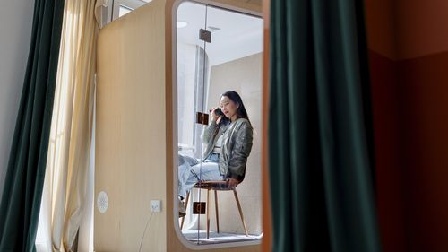 Local de trabalho híbrido, profissional de negócios feminino sentado na mesa falando ao telefone