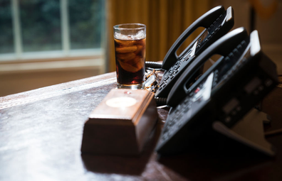 A glass of iced soda is seen on the Resolute Desk as President Donald Trump speaks to media