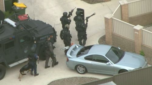 Heavily-armed police move towards the suspect's house. (9NEWS)