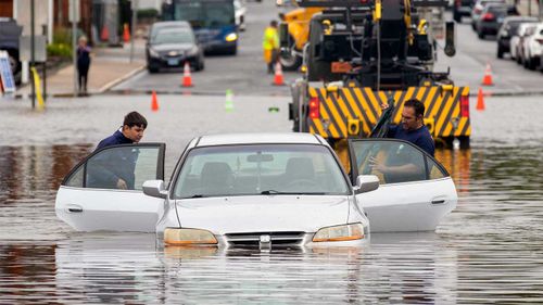 A father and son try and retrieve a car stuck in floodwaters caused by Tropical Storm Elsa in Connecticut.