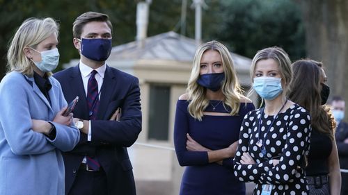 White House press secretary Kayleigh McEnany, third from left, waits with others as President Donald Trump prepares to leave the White House to go to Walter Reed National Military Medical Centre.