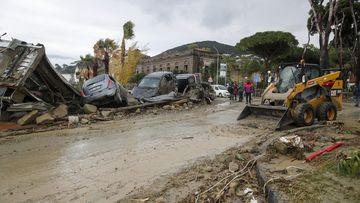 Rescuers remove mud from a street after heavy rainfall triggered landslides in Italy.