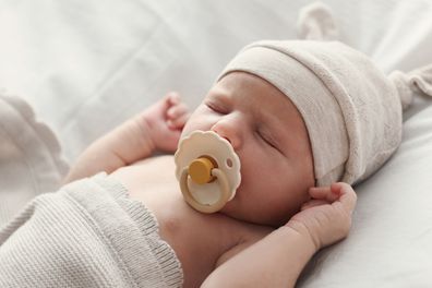 Adorable little baby with pacifier sleeping in bed, closeup