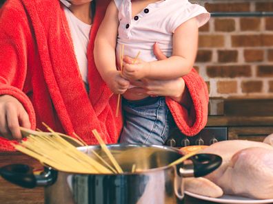 Tired mum cooking holding child