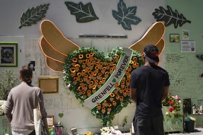 People observe the memorial, near to the remains of the Grenfell Tower, in London, Tuesday, June 14, 2022. Tuesday marks the fifth anniversary of the fire that killed 72 people 