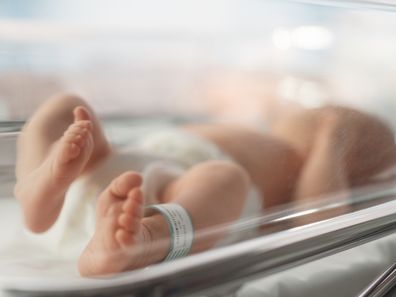 Cute Little Caucasian Newborn Baby Lying in Bassinet in a Maternity Hospital. Portrait of a Tiny Playful and Energetic Child with a Name ID Tag on the Leg. Healthcare, Pregnancy and Motherhood Concept