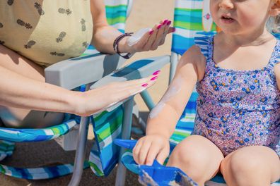 Stock photo of a woman applying sunscreen on a little girl.