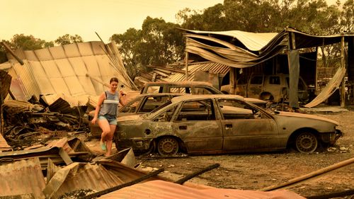 A woman picks through the burnt-out remains of a property in Tingha.